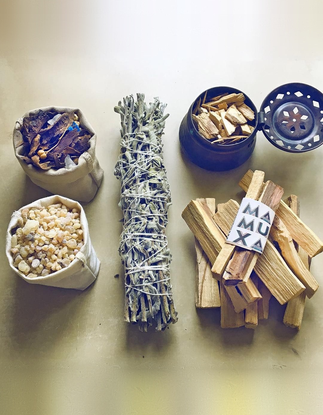 Bakhoor and frankincense resin in cotton pouches, an Anatolian sage bundle, palo santo sticks and a copper incense burner